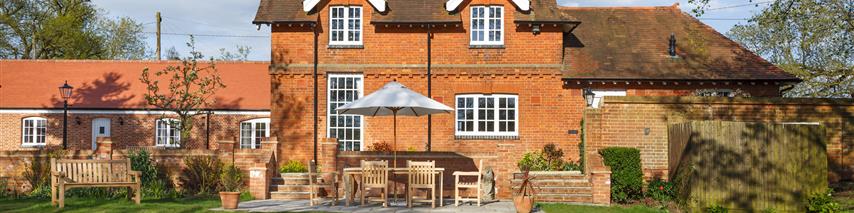 Large house with garden, umbrella covering outdoor table and chairs