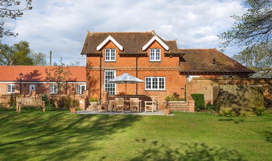 Large house with garden, umbrella covering outdoor table and chairs